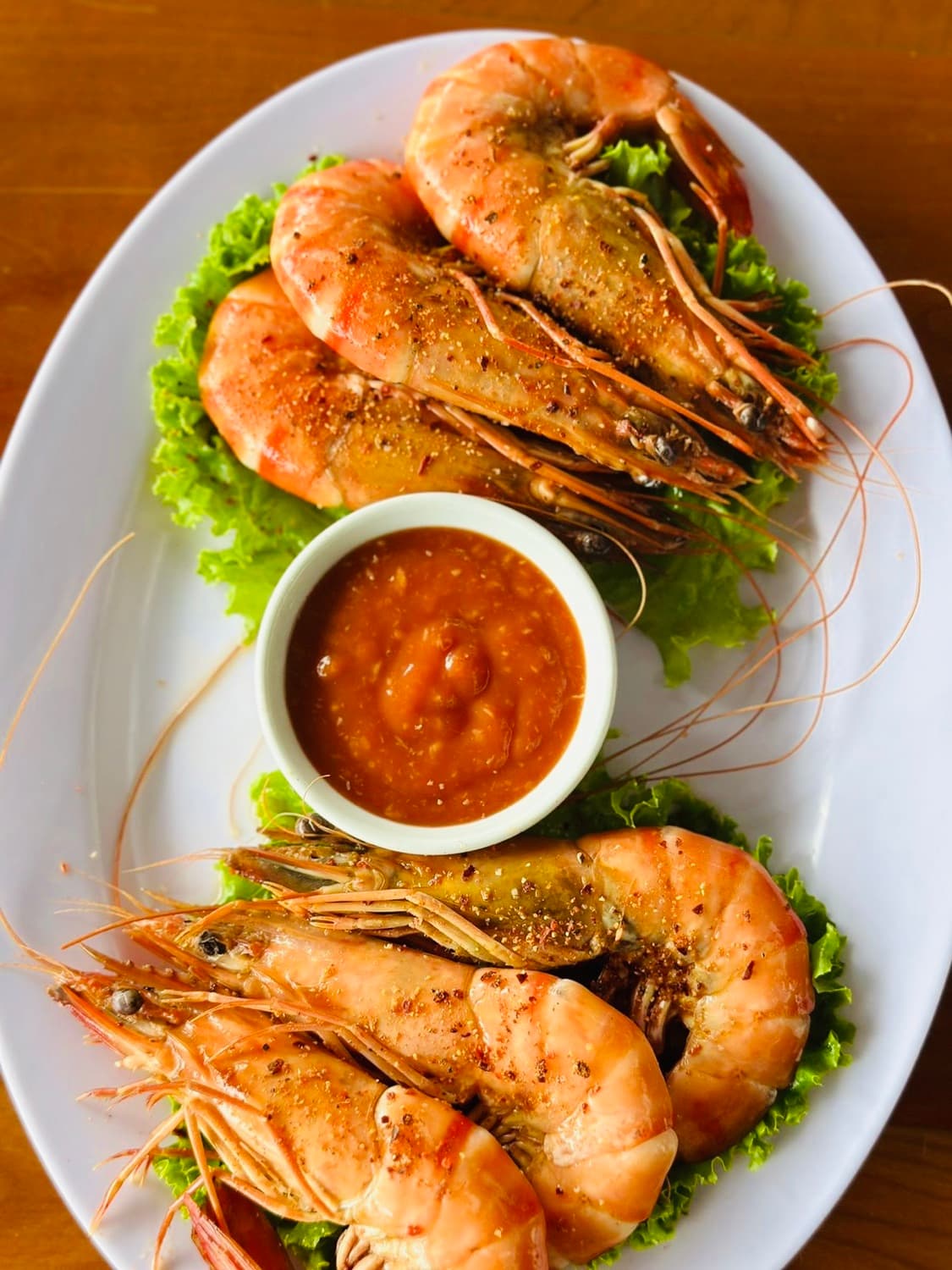 Một đĩa tôm với xà lách và nước chấm.