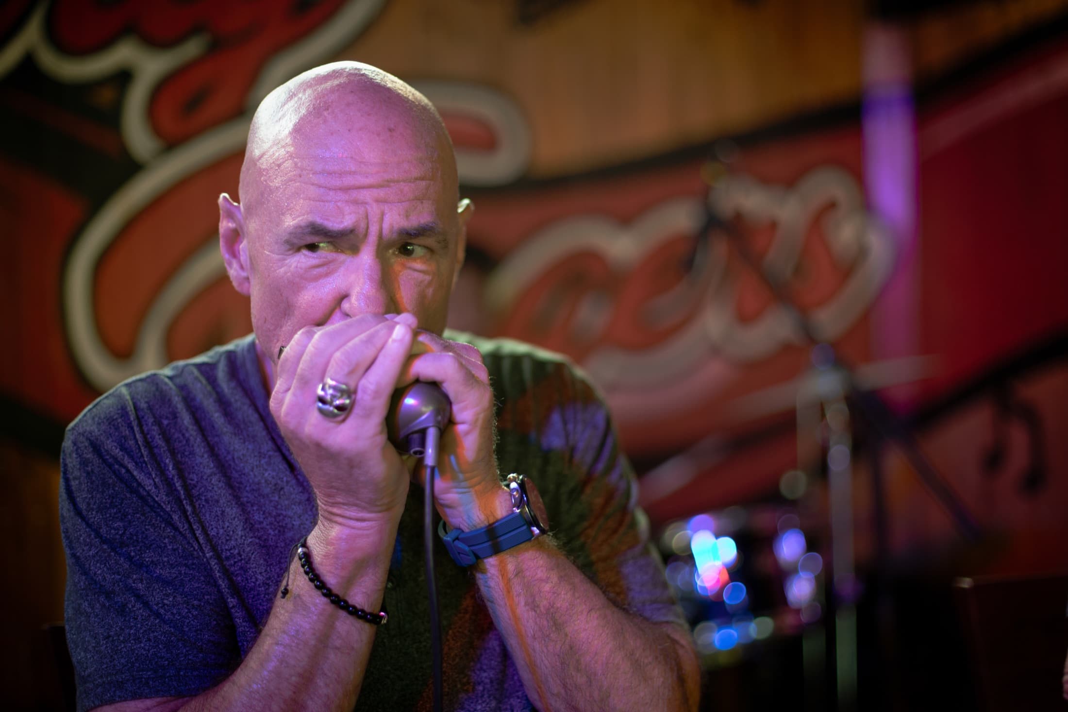 A man playing the harmonica in front of the Dirty Fingers logo.